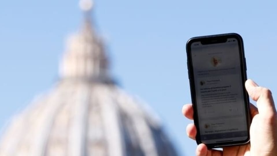 A man shows the 'Click to Pray' app, a smartphone app designed to allow the faithful to pray with a click, near St. Peter's Square at the Vatican, October 19, 2021. 