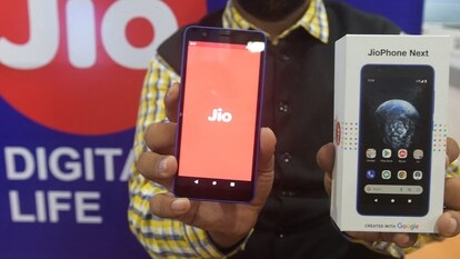 A shopkeeper poses for a picture with the new JioPhone Next 4G smartphone during a media preview in Ahmedabad.