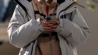 A pedestrian uses an Apple iPhone smartphone