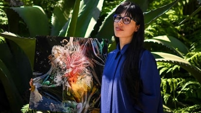 Argentinian artist Sofia Crespo holds one of her works as she poses for a photo at the Estrela garden in Lisbo.