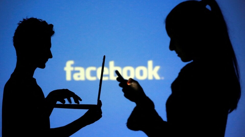 FILE PHOTO: People are silhouetted as they pose with laptops in front of a screen projected with a Facebook logo, in this picture illustration taken in Zenica October 29, 2014. REUTERS/Dado Ruvic/File Photo