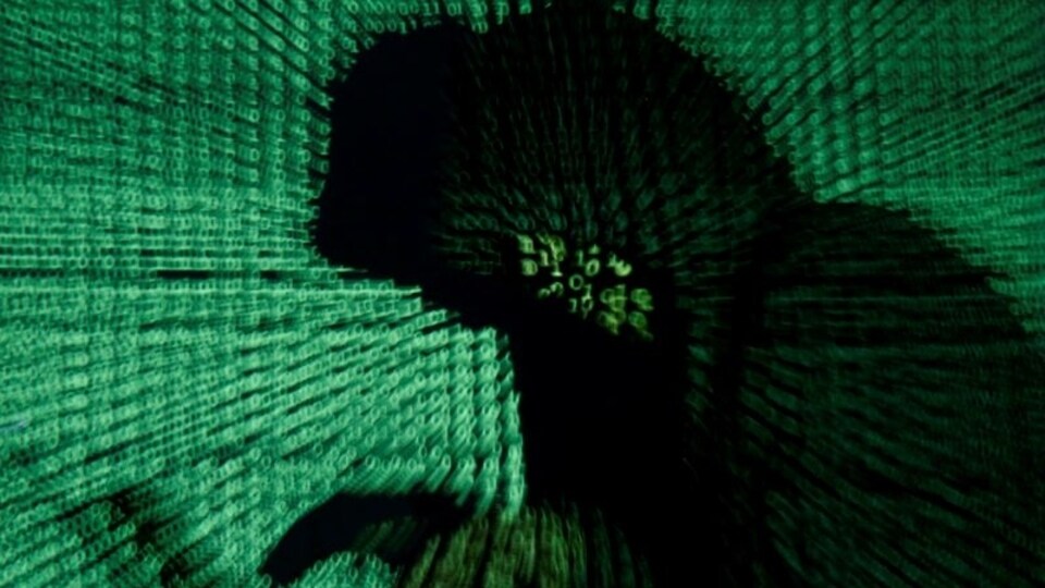 FILE PHOTO: A man holds a laptop computer as cyber code is projected on him in this illustration picture taken on May 13, 2017. REUTERS/Kacper Pempel