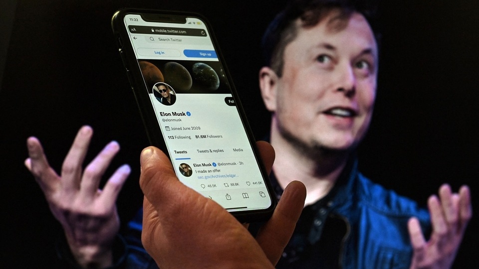 (FILES) In this file photo illustration, a phone screen displays the Twitter account of Elon Musk with a photo of him shown in the background, on April 14, 2022, in Washington, DC. - Elon Musk pulled the plug on his deal to buy Twitter on July 8, 2022, accusing the company of 