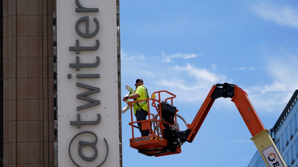 A workman removes a character from a sign on the Twitter headquarters building in San Francisco, Monday, July 24, 2023. Elon Musk