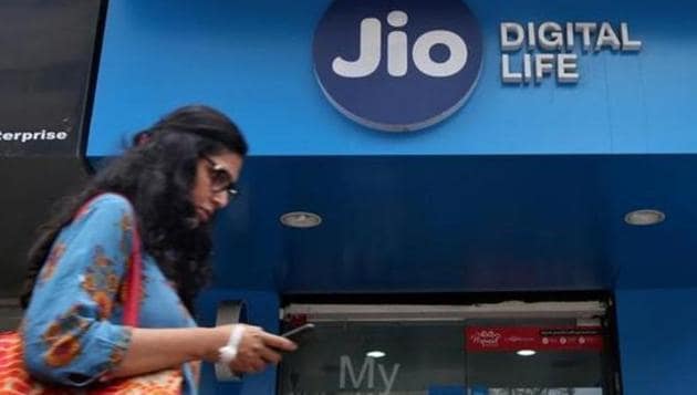 A woman checks her mobile phone as she walks past a mobile store of Reliance Industries' Jio telecoms unit in Mumbai.