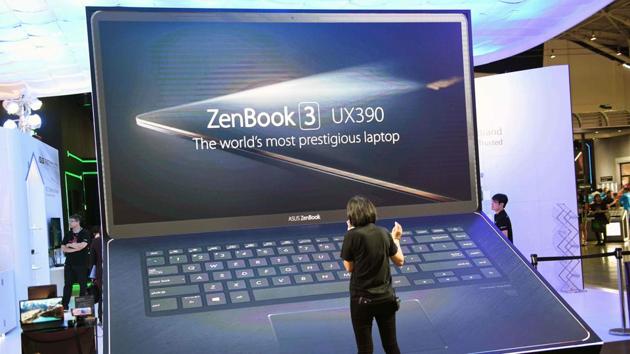 A staff of Taiwan's Asus checks a giant laptop mockup of a ZenBook computer during Computex 2018 at the Nangang Exhibition Center in Taipei on June 5, 2018.