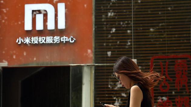 A woman walks past a Xiaomi logo outside a Xiaomi service center in Beijing.