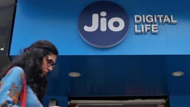 A woman checks her mobile phone as she walks past a mobile store of Reliance Industries' Jio telecoms unit, in Mumbai.