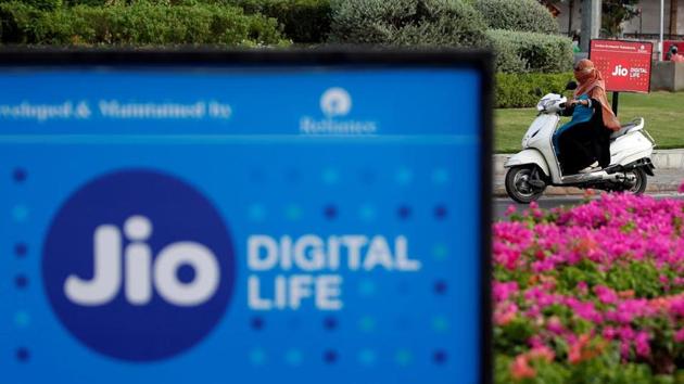 A woman rides her scooter past advertisements of Reliance Industries' Jio telecoms unit, in Ahmedabad, India, July 5, 2018..