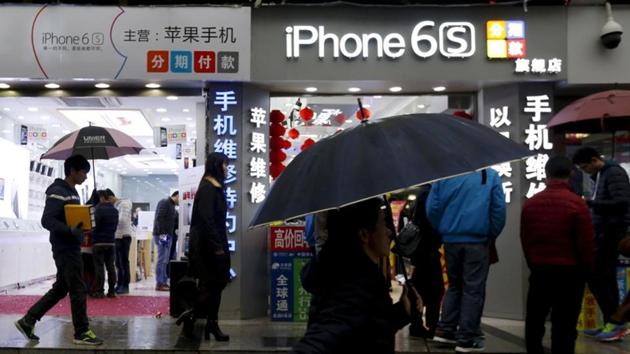 People walk past stores promoting the Apple iPhone 6S in the southern city of Shenzhen, China January 26, 2016.
