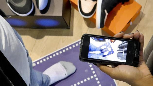 Nike officials demonstrate the company's foot-scanning tool on its app that will measure and remember the length, width and other dimensions of customers' feet after they point a smartphone camera to their toes.