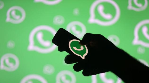 A man poses with a smartphone in front of displayed Whatsapp logo in this illustration September 14, 2017.