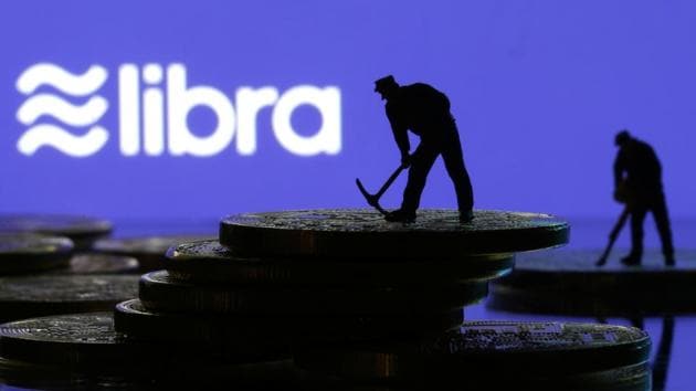 Small toy figures are seen on representations of virtual currency in front of the Libra logo in this illustration picture, June 21, 2019.