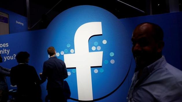 FILE PHOTO: Attendees walk past a Facebook logo during Facebook Inc's F8 developers conference in San Jose, California, U.S., April 30, 2019.