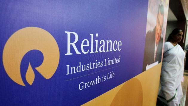 FILE PHOTO: A woman walks past a poster of Reliance Industries installed outside the venue of the company's annual general meeting in Mumbai June 7, 2012. REUTERS/Vivek Prakash/File Photo