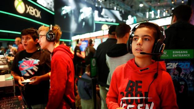 Boys play video games at the booth of Microsoft's Xbox during the first day of Europe's leading digital games fair Gamescom, which showcases the latest trends of the computer gaming scene.