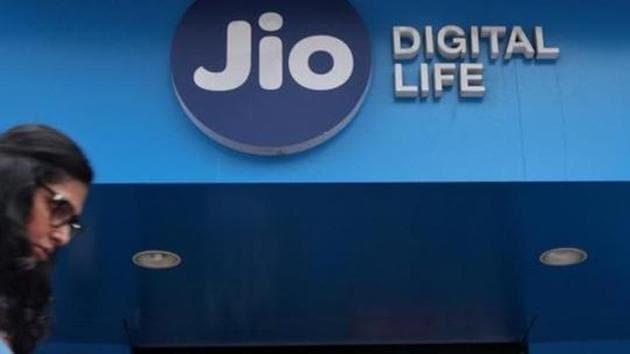 A woman checks her mobile phone as she walks past a mobile store of Reliance Industries' Jio telecoms unit, in Mumbai, July 11, 2017.