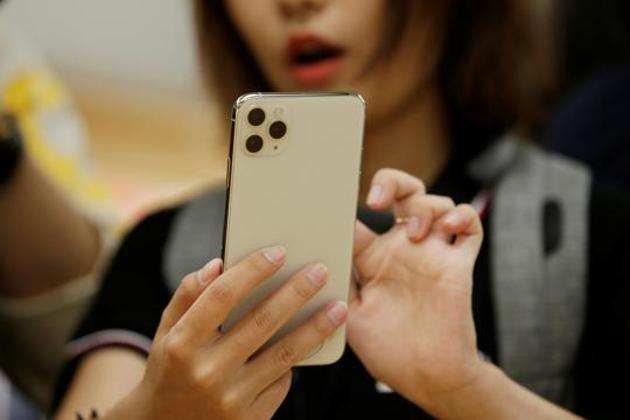 A woman holds an iPhone 11 Pro Max while giving a live broadcast after it went on sale at the Apple Store in Beijing, China, September 20, 2019. REUTERS/Jason Lee - RC14406658D0