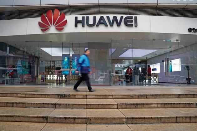 A man walks by a Huawei logo at a shopping mall in Shanghai