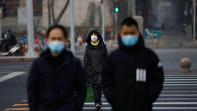 People wearing masks walk across a street as the country is hit by an outbreak of the new coronavirus, in Beijing, China January 28, 2020.