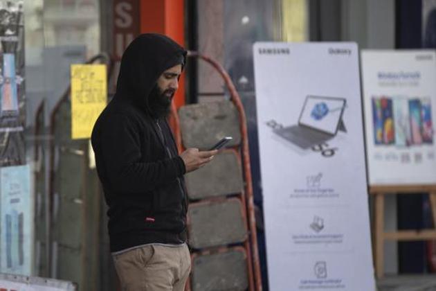 In this Jan. 30, 2020, photo, a Kashmiri man browses the internet on his mobile phone outside a shop in Srinagar, Indian controlled Kashmir. Six months after India stripped restive Kashmir of its semi-autonomy, enforcing a total communications blackout, it has restored limited internet at slow speeds with access only to government-approved websites. Since Modi came into power in 2014, the internet has been suspended more than 365 times in India, according to the global digital rights group Access Now. (AP Photo/Dar Yasin)