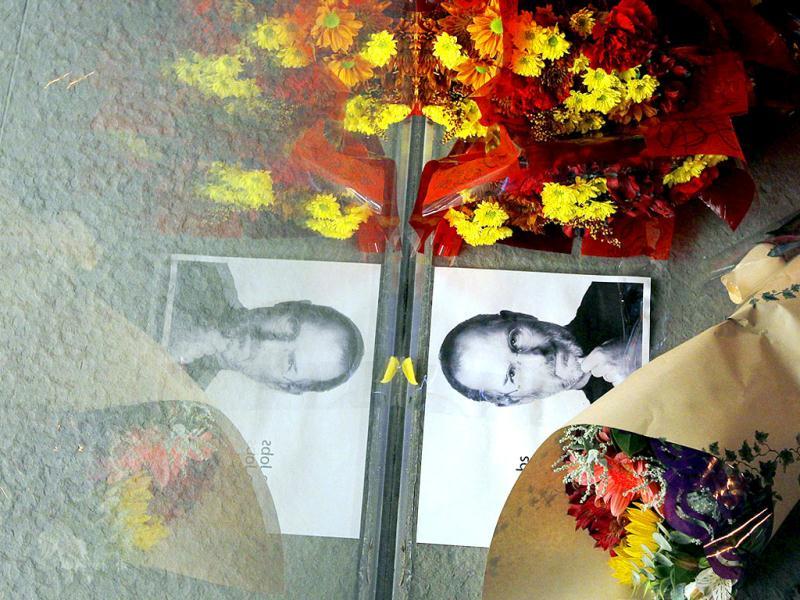 Flowers and a photograph of Steve Jobs are placed against the window outside an Apple store in Boston, Massachusetts. Flowers and a photograph of Steve Jobs are placed against the window outside an Apple store in Boston, Massachusetts.