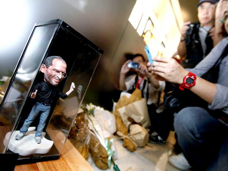 A man takes pictures of a figure of Apple founder and former CEO Steve Jobs near flowers laid in his tribute at an Apple retail store in Hong Kong. A man takes pictures of a figure of Apple founder and former CEO Steve Jobs near flowers laid in his tribute at an Apple retail store in Hong Kong.