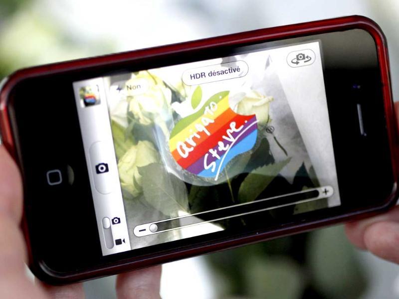 A woman uses her iPhone to take a photo of a sticker on a flower offered in memory of Apple co-founder Steve Jobs, at the entrance of the Ginza Apple store in Tokyo. A woman uses her iPhone to take a photo of a sticker on a flower offered in memory of Apple co-founder Steve Jobs, at the entrance of the Ginza Apple store in Tokyo.