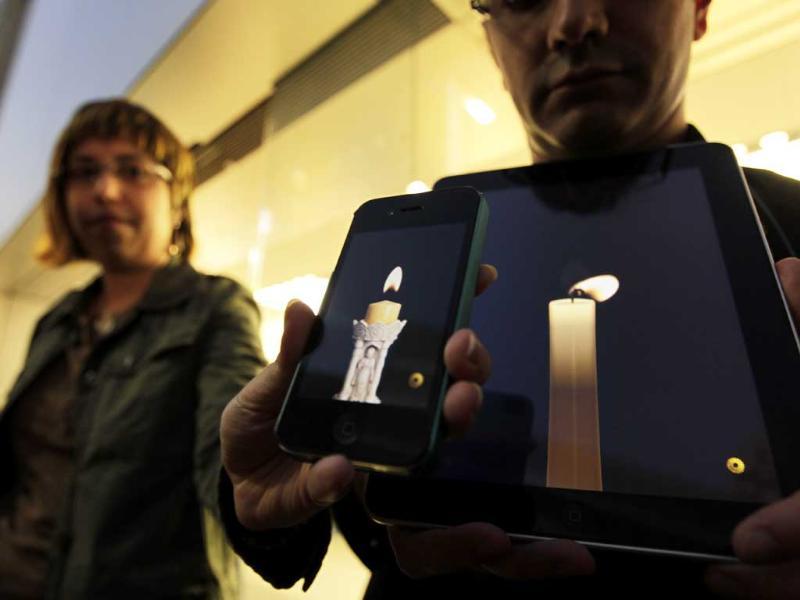 Apple computer fans hold their iPhone and iPad displaying candle graphics during a candle light vigil to pay tribute to Steve Jobs, the Apple founder and former CEO, at an Apple Store in the Ginza shopping district in Tokyo. Apple computer fans hold their iPhone and iPad displaying candle graphics during a candle light vigil to pay tribute to Steve Jobs, the Apple founder and former CEO, at an Apple Store in the Ginza shopping district in Tokyo.