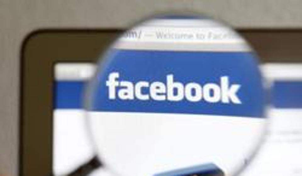 A Facebook logo on a computer screen is seen through a magnifying glass held by a woman in Bern. A Facebook logo on a computer screen is seen through a magnifying glass held by a woman in Bern.