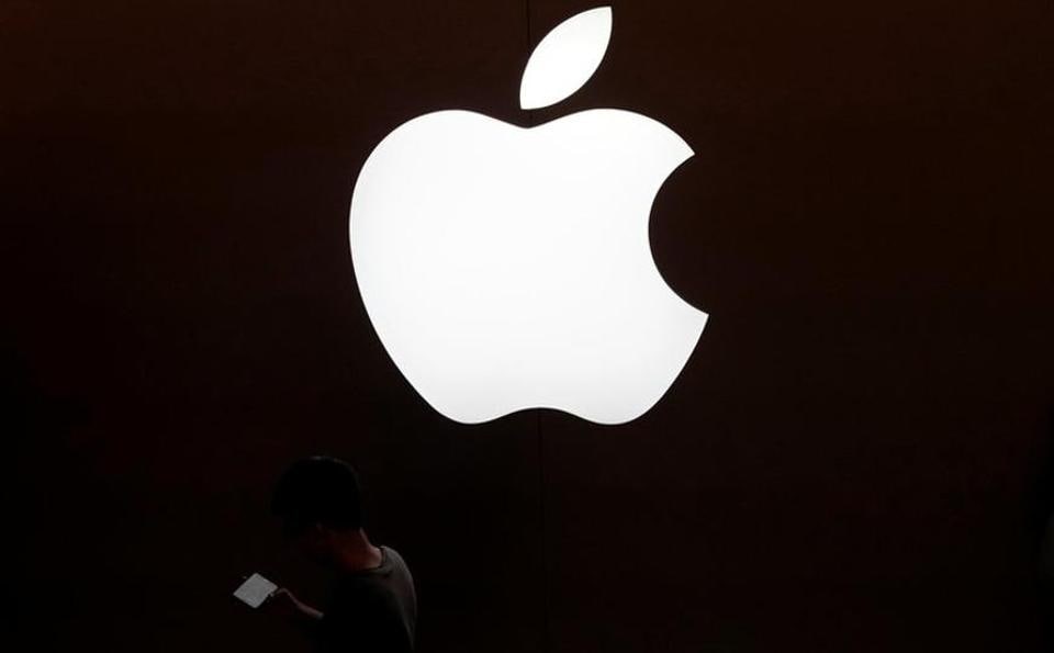 A man looks at the screen of his mobile phone in front of an Apple logo outside its store in Shanghai, China.