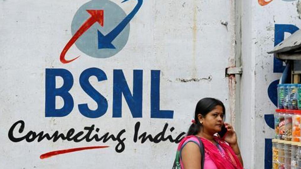 A woman speaks on her mobile phone in front of the logo of Bharat Sanchar Nigam Ltd (BSNL) painted on a wall outside its office in Kolkata, August 24, 2017.