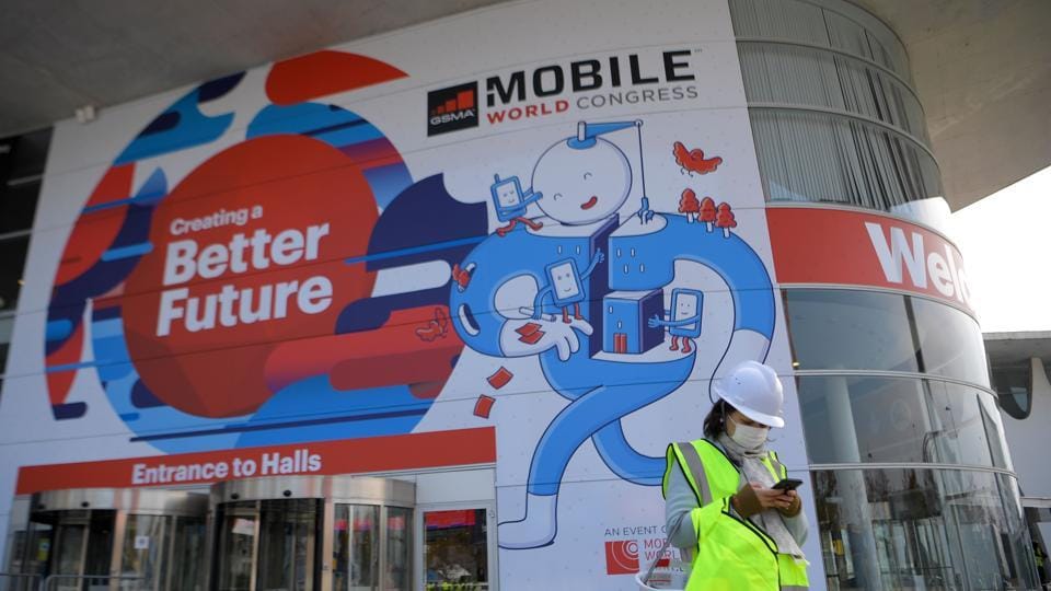 A worker of Mobile World Congress uses a smartphone in front of the venue's entrance on February 23, 2018, ahead of the start of the world's biggest mobile fair, held from February 26 to March 1.