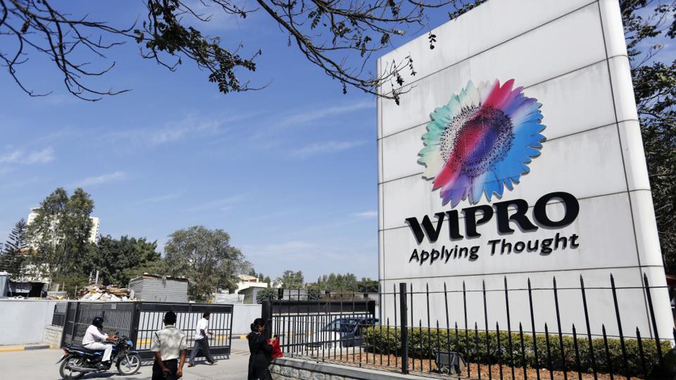 Employees walk past Wipro Ltd. signage as they enter the company's campus in Bangalore, India. Photographer: Vivek Prakash/BLOOMBERG