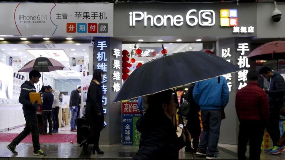 People walk past stores promoting the Apple iPhone 6S in the southern city of Shenzhen, China January 26, 2016.