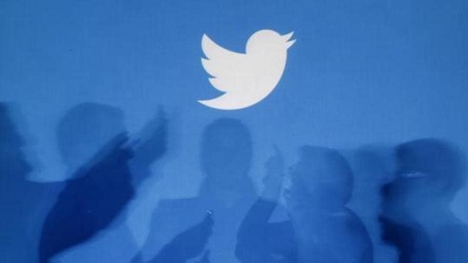 The shadows of people holding mobile phones are cast onto a backdrop projected with the Twitter logo in this illustration picture taken in Warsaw September 27, 2013.