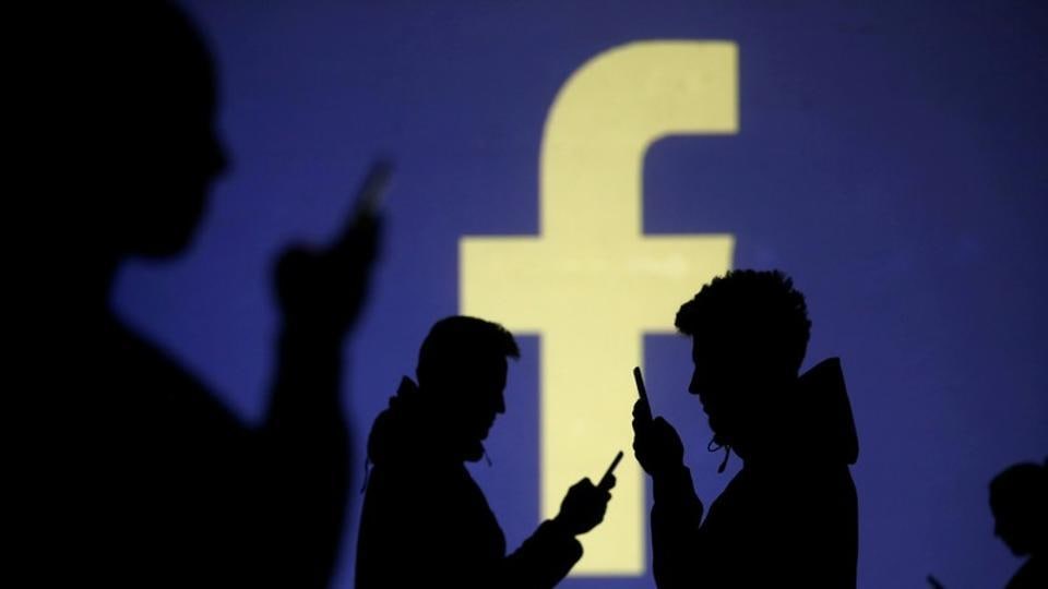 FILE PHOTO: Silhouettes of mobile users are seen next to a screen projection of Facebook logo in this picture illustration taken March 28, 2018. REUTERS/Dado Ruvic/Illustration/File Photo