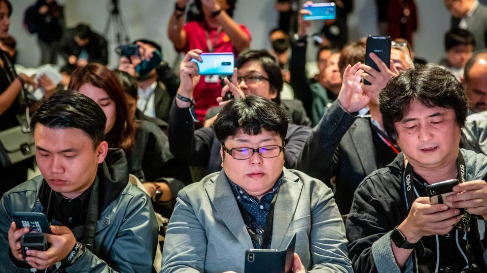 Attendees check their smartphone devices during a Guangdong Oppo Electronics Co. launch event ahead of the MWC Barcelona in Barcelona, Spain, on Saturday, Feb. 23, 2019.