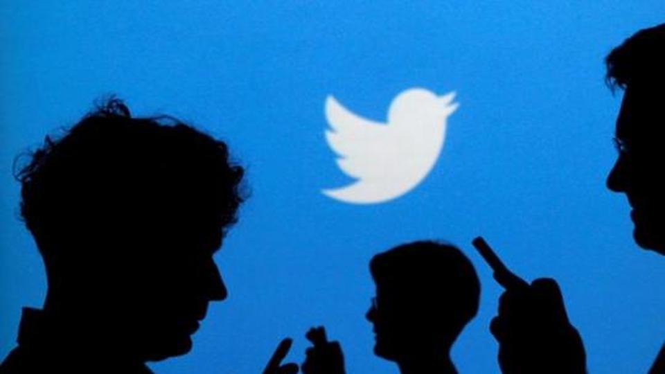 People holding mobile phones are silhouetted against a backdrop projected with the Twitter logo in this illustration picture taken in Warsaw September 27, 2013. REUTERS/Kacper Pempel/Illustration/Files