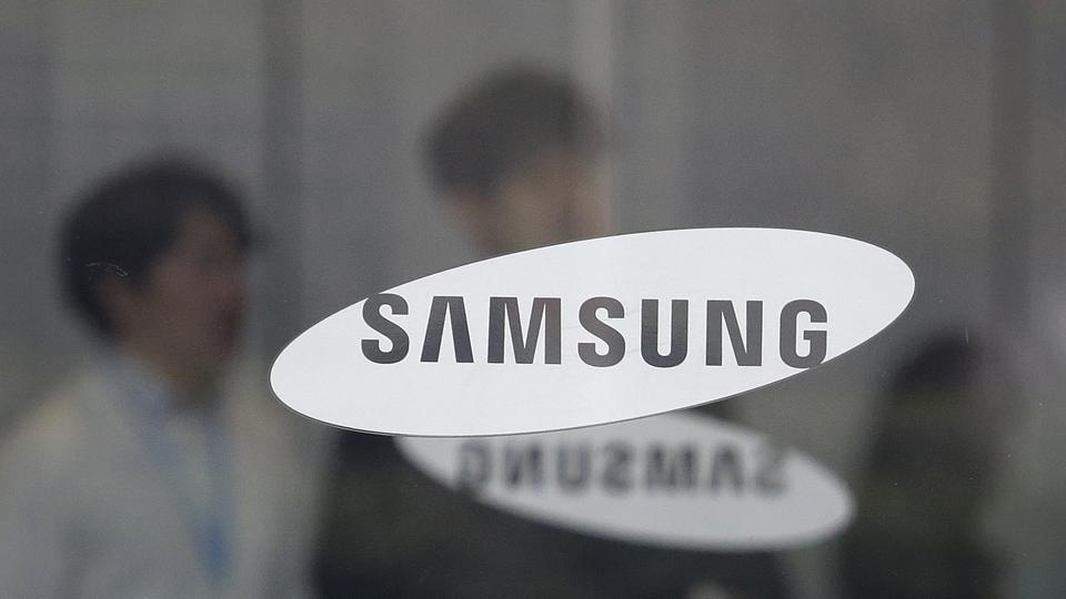 Employees walk past the logo of the Samsung Electronics Co. at its office in Seoul, South Korea, Friday, April 5, 2019. Samsung Electronics Co. said Friday its operating profit for the last quarter likely fell more than 60% from a year earlier amid falling memory chip prices and slowing demand for display panels. (AP Photo/Ahn Young-joon)