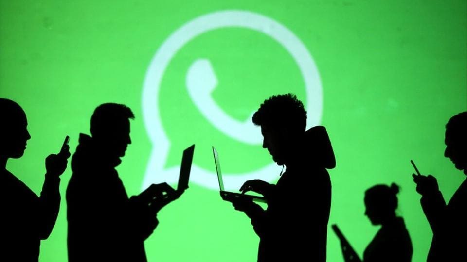 Silhouettes of laptop and mobile device users are seen next to a screen projection of Whatsapp logo in this picture illustration taken March 28, 2018.
