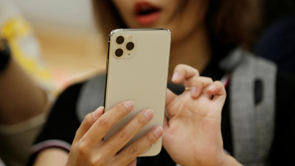 A woman holds an iPhone 11 Pro Max while giving a live broadcast after it went on sale at the Apple Store in Beijing, China, September 20, 2019.