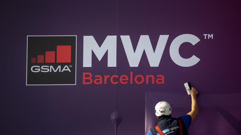 A worker fixes a poster announcing the Mobile World Congress 2020 in a conference venue in Barcelona, Spain, Tuesday, Feb. 11, 2020. Intel Mobile is the latest company announcing that is pulling out of the Mobile World Congress scheduled to be held in Barcelona in late February. Authorities still seem to be committed to hold it, meeting foreign diplomats on Tuesday to brief on the efforts to prevent any spread of the new coronavirus virus during the industry show. (AP Photo/Emilio Morenatti)