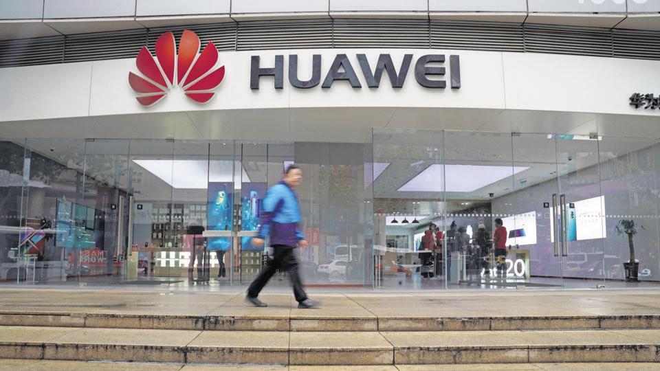A man walks by a Huawei logo at a shopping mall in Shanghai, China December 6, 2018.