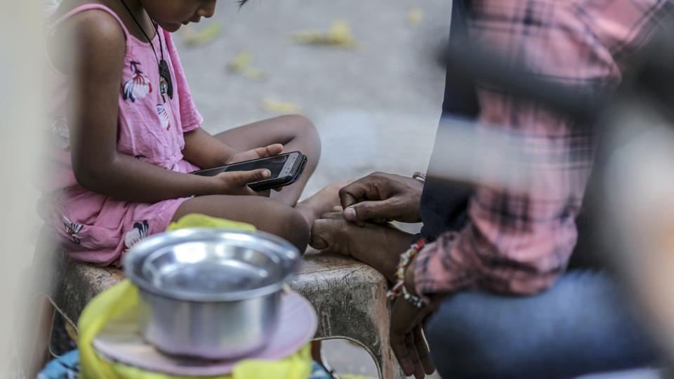 A child uses a smartphone while sitting on the street in Mumbai, India.
