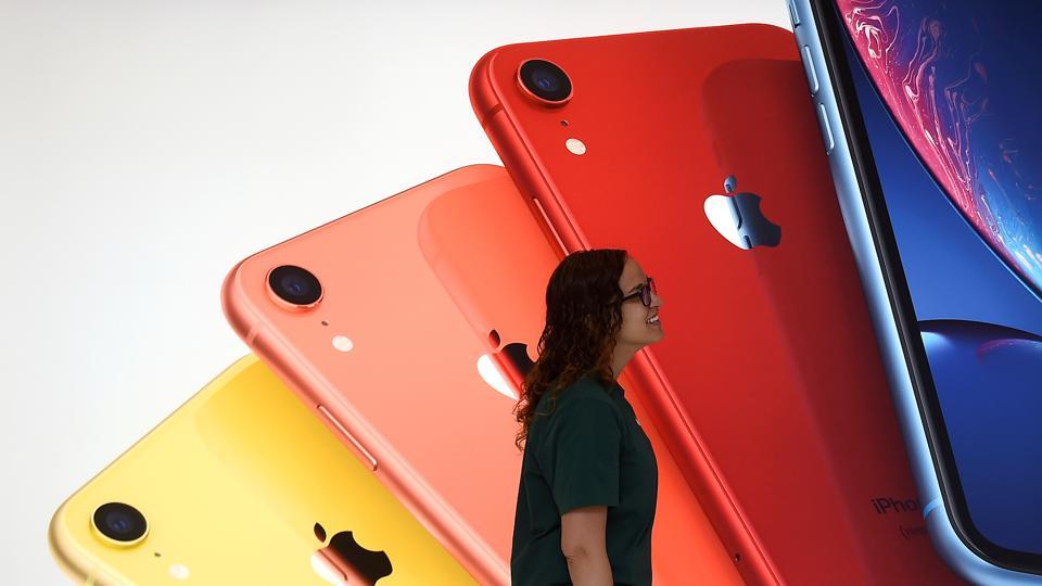 FILE PHOTO: An Apple Store employee walks past an illustration of iPhones at the new Apple Carnegie Library during the grand opening and media preview in Washington, U.S., May 9, 2019. REUTERS/Clodagh Kilcoyne/File Photo