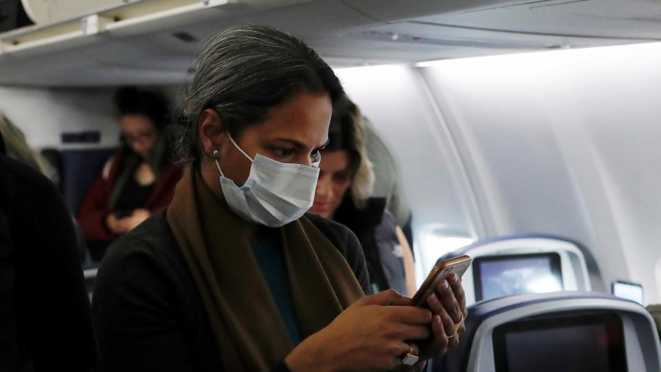 A woman in a face mask checks her phone.