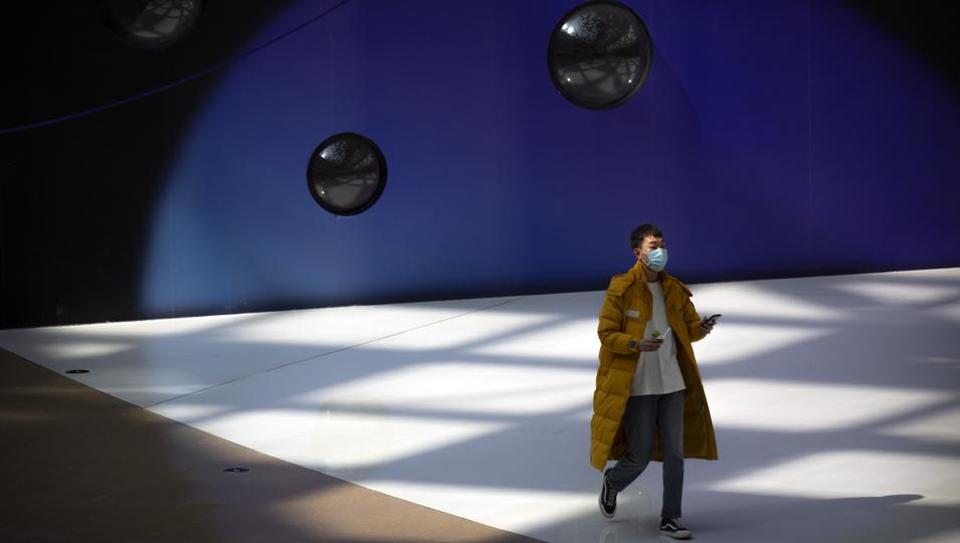 A man wears a face mask as he walks through a mostly empty shopping mall in Beijing, Saturday, March 7, 2020. Crossing more borders, the new coronavirus hit a milestone, infecting more than 100,000 people worldwide as it wove itself deeper into the daily lives of millions, infecting the powerful, the unprotected poor and vast masses in between.