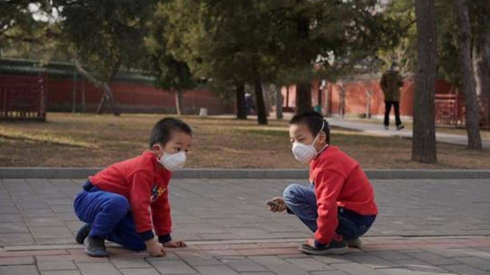 Children wearing face masks play at a park.