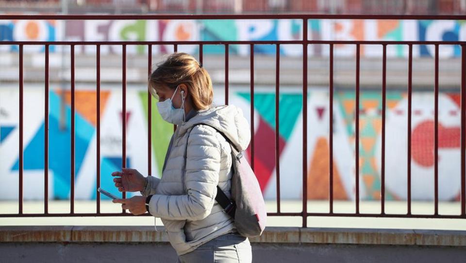 A woman, wearing a protective face mask, walks outside a closed school on the first day of a two-week clousure of all kindergartens, schools and universities in the Madrid region as a precaution against coronavirus in Madrid, Spain, March 11, 2020.